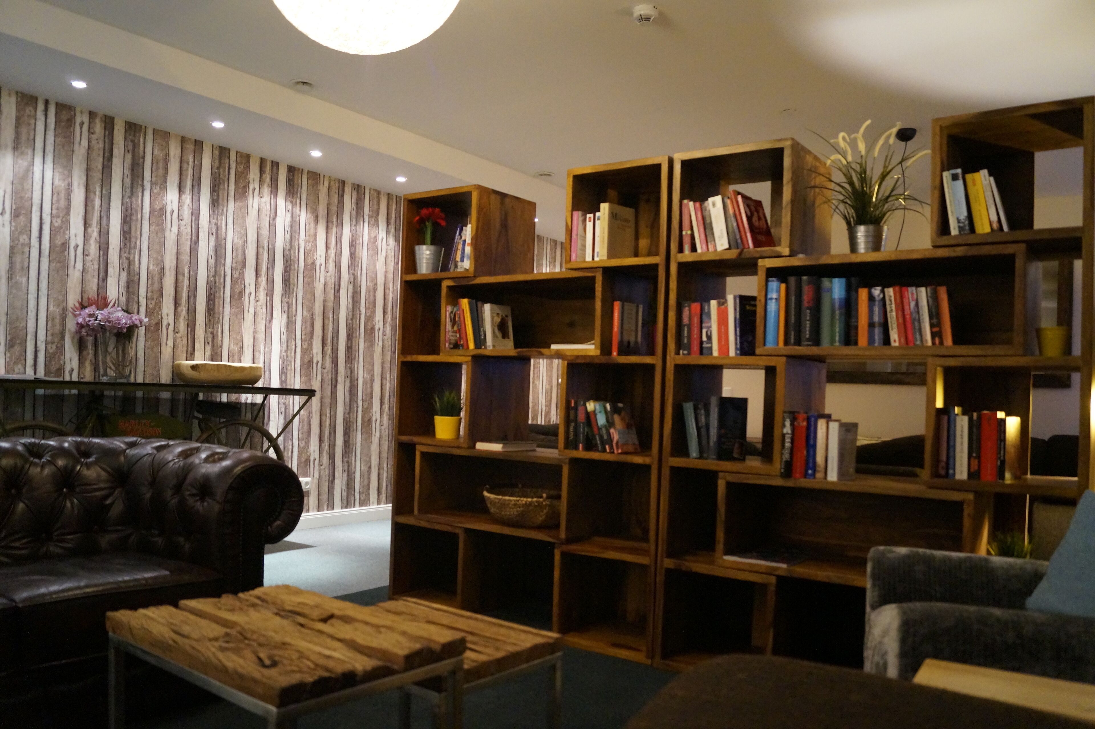A cozy living room with a leather sofa, a wooden coffee table, and a bookshelf filled with books.