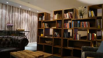 A cozy living room with a leather sofa, a wooden coffee table, and a bookshelf filled with books.