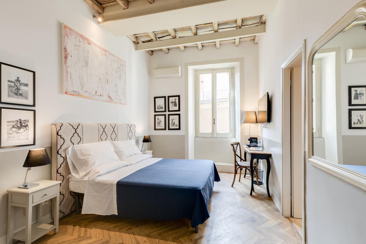 Une chambre à coucher comprenant un lit, une table de chevet, une lampe et un bureau avec une chaise.