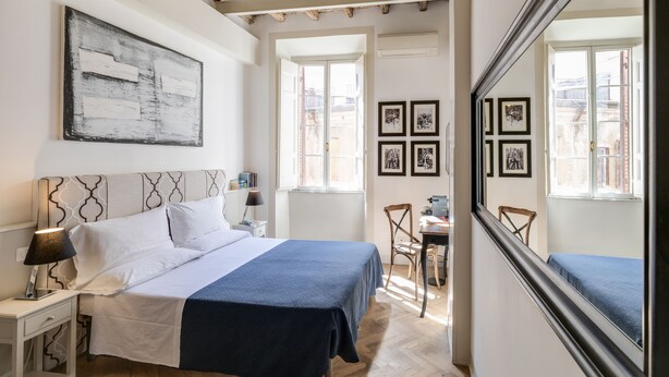 Un dormitorio con cama, mesita de noche, lámpara y un espejo grande.