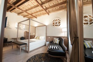 Un dormitorio con cama con dosel, un escritorio, una silla y un sofá.