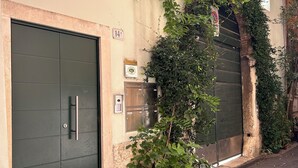 A building with a large metal door, a small sign, and some greenery. - Residenza Bonifacio (Verona)