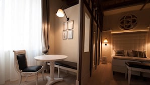 A cozy room with a round table, a cushioned bench, and a sofa. There are framed pictures on the wall and a decorative wall piece. - Residenza Bonifacio (Verona)