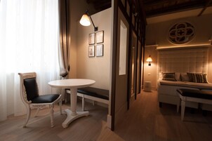 Una habitación acogedora con una mesa redonda, un banco acolchado y un sofá. Hay cuadros en la pared y un adorno decorativo.