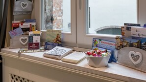 A window ledge with various items including books, postcards, and a bowl of chocolates. - Residenza Bonifacio (Verona)