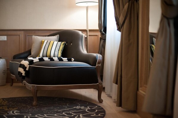 A room with a dark upholstered armchair, a patterned rug, a lamp, and curtains. - Residenza Bonifacio (Verona)