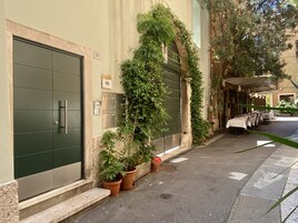Un edificio con puerta verde, plantas en macetas y mesas al aire libre.
