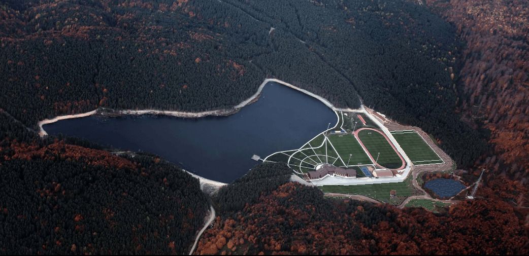 An aerial view of a lakeside property with a large lake, a running track, and a small pond.