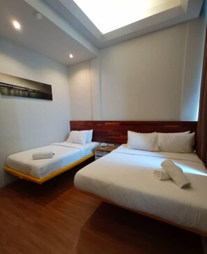 A hotel room with two single beds, a wooden headboard, a nightstand, and a ceiling light. - The Riverbank Hotel (Kuantan)