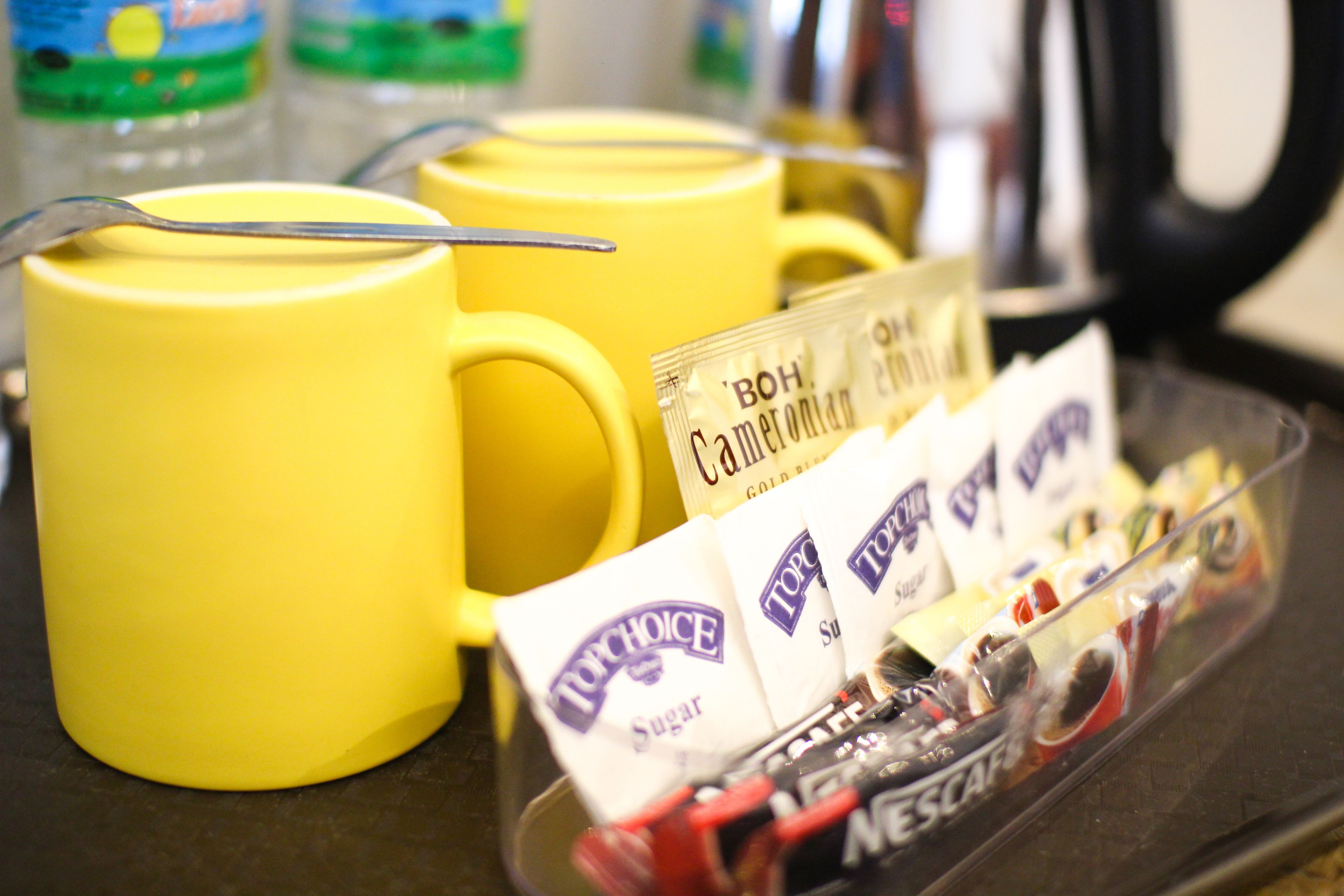 A tray with yellow mugs and sugar packets.