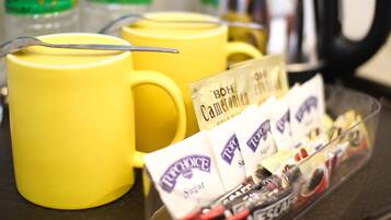 A tray with yellow mugs and sugar packets.
