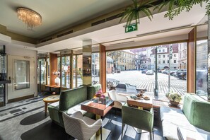 A hotel lobby with seating, a chandelier, and a view of the street. - Residence Mysterius Old Town  (Prague)