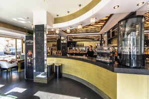 A bar area with a curved counter, a cash register, and a variety of bottles and glasses. - Residence Mysterius Old Town  (Prague)