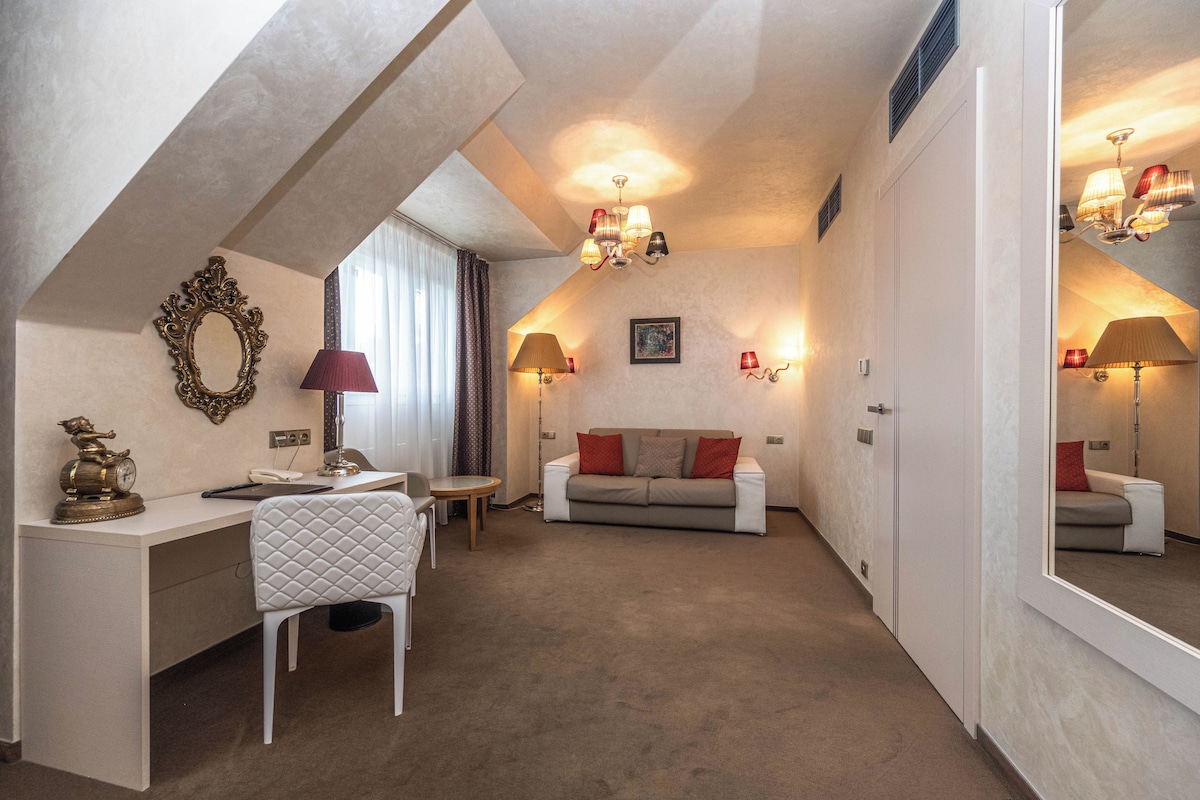 A room with a desk, chair, sofa, and lamps.