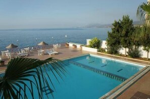 Una piscina al aire libre, sombrillas, sillones reclinables de piscina