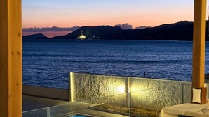 A dining area with a pool view, a table set for two, and a sunset over the water. - Lades Hotel (Silifke)