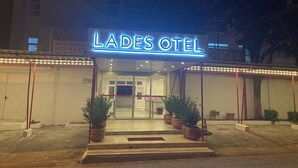 The exterior of Lades Hotel with a neon sign, entrance, potted plants, and a visible door. - Lades Hotel (Silifke)