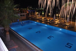 Una piscina al aire libre, sombrillas, sillones reclinables de piscina