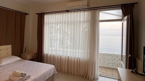 A hotel room with a bed, a desk, a window with curtains, and an air conditioning unit. - Lades Hotel (Silifke)