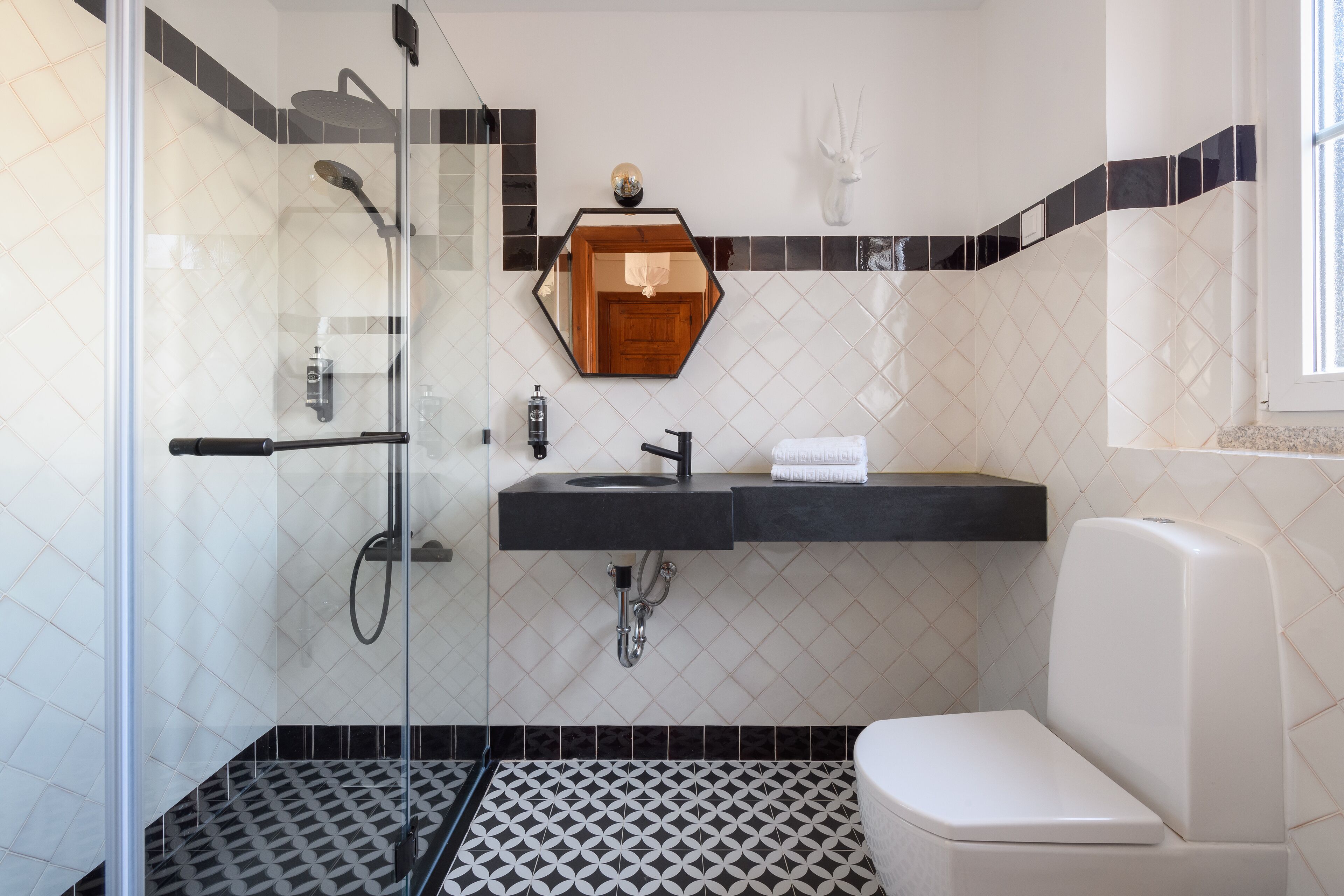 Une salle de bain avec une douche à parois de verre, un lavabo noir et des toilettes blanches.