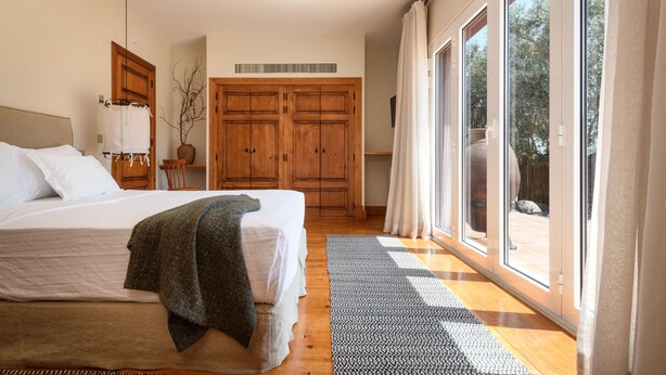 A bedroom with a large bed, wooden wardrobe, and a sliding glass door to a balcony. - Casa do Governador (Évora)