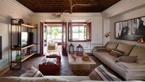 A spacious living room with a brick ceiling, a sofa, a coffee table, and a bookshelf. - Casa do Governador (Évora)