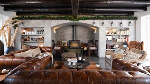 A cozy living room with leather sofas, a fireplace, and shelves with books and decorative items. - Casa do Governador (Évora)