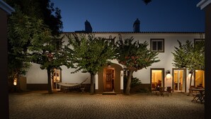A courtyard with a cobblestone floor, a hammock, and a dining area with chairs and tables. - Casa do Governador (Évora)