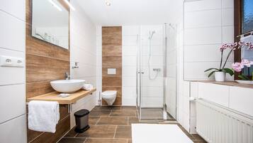 A modern bathroom with a large sink, toilet, and shower.