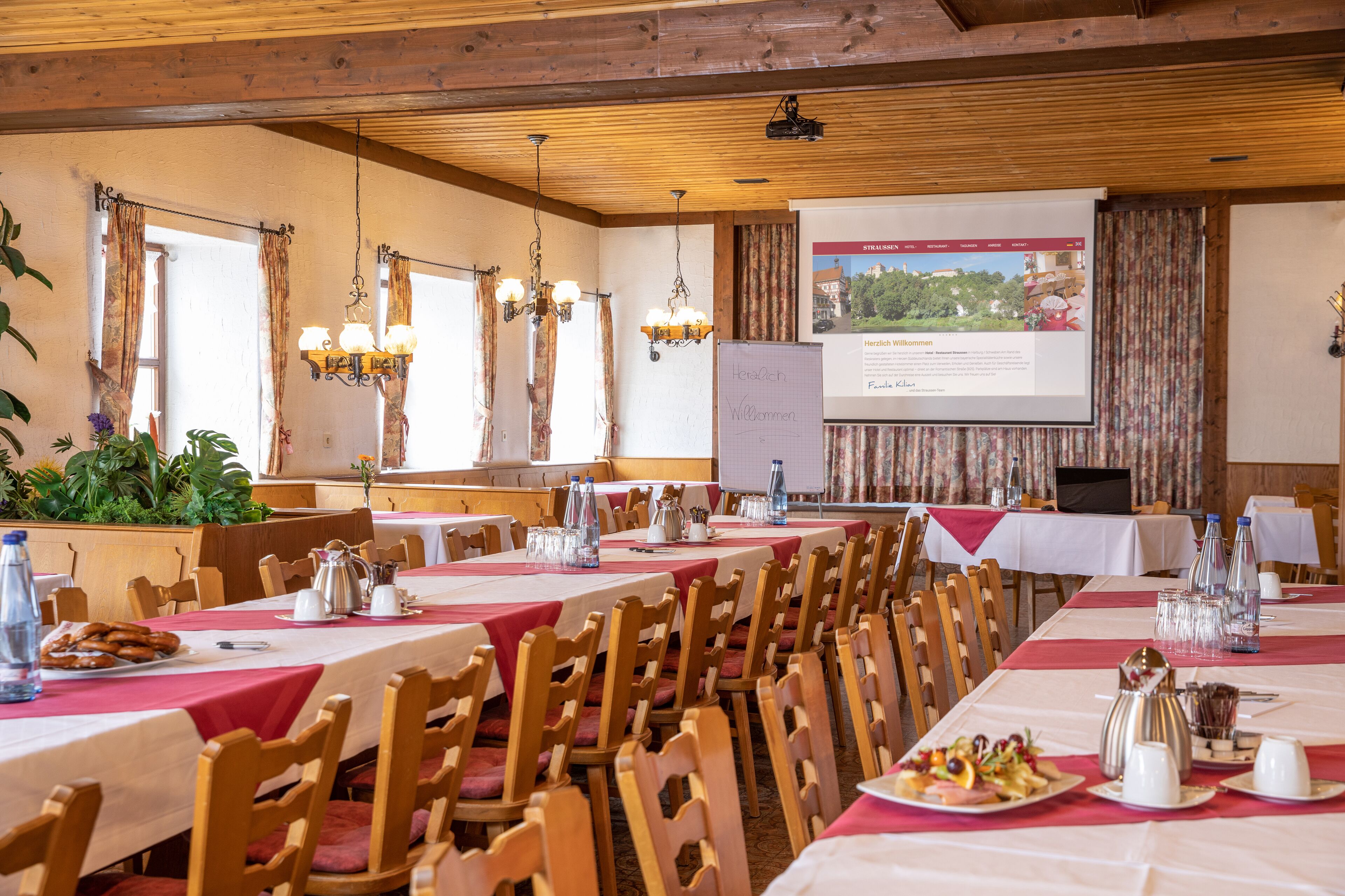 A conference room with tables set for a meeting, a projection screen, and a whiteboard.