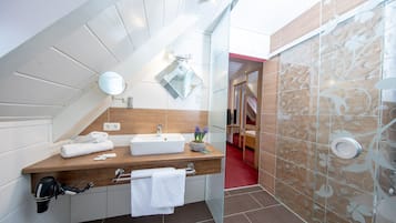 Une salle de bain moderne avec un meuble-lavabo en bois, un miroir, un lavabo et un espace douche agrémenté de carreaux à motifs.