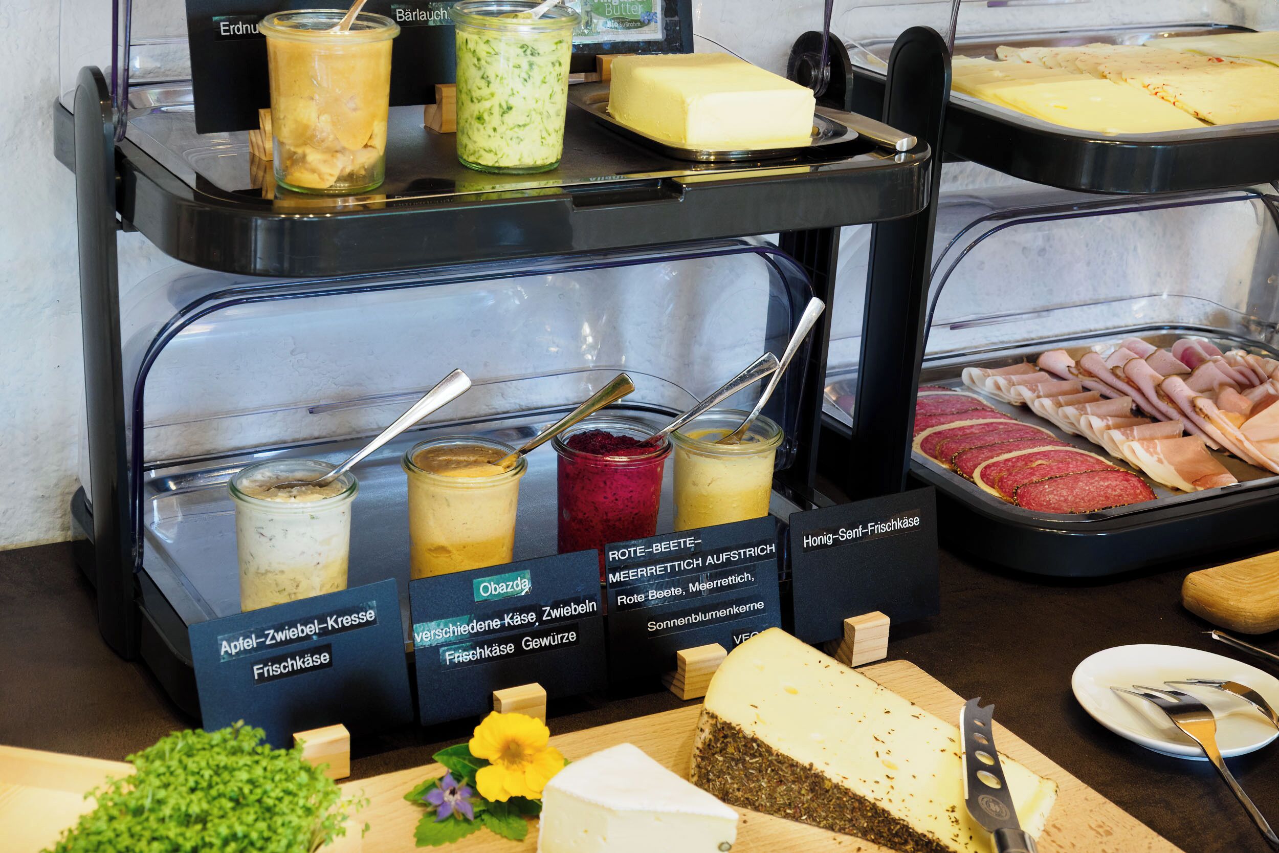 A buffet with various food items including cheese, meats, and beverages.