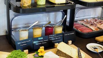 Ein Buffet mit verschiedenen Speisen, darunter Käse, Fleisch und Getränke.