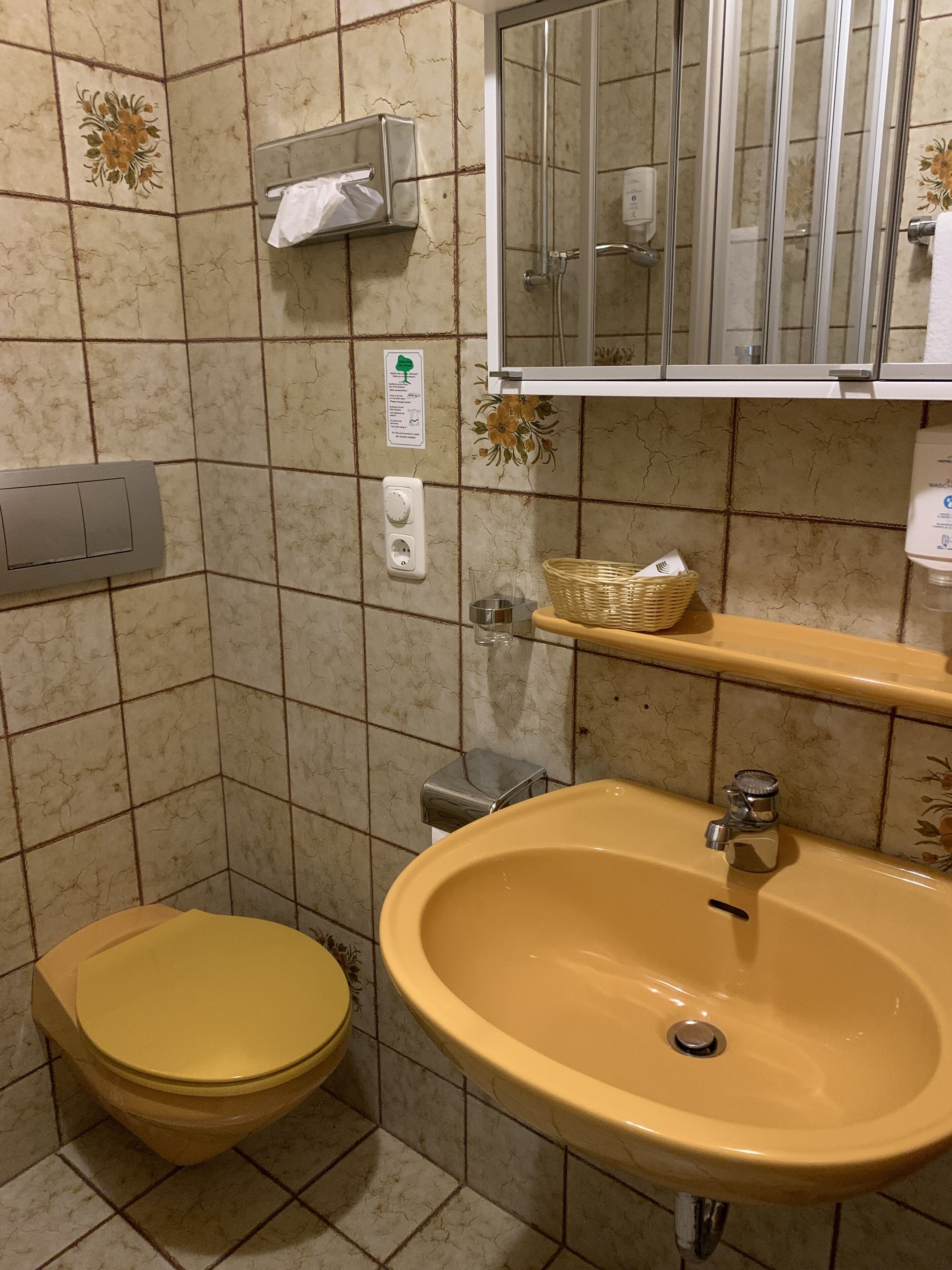 A bathroom with a yellow sink, a toilet, a mirror, and a shower enclosure.