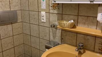 A bathroom with a yellow sink, a toilet, a mirror, and a shower enclosure.