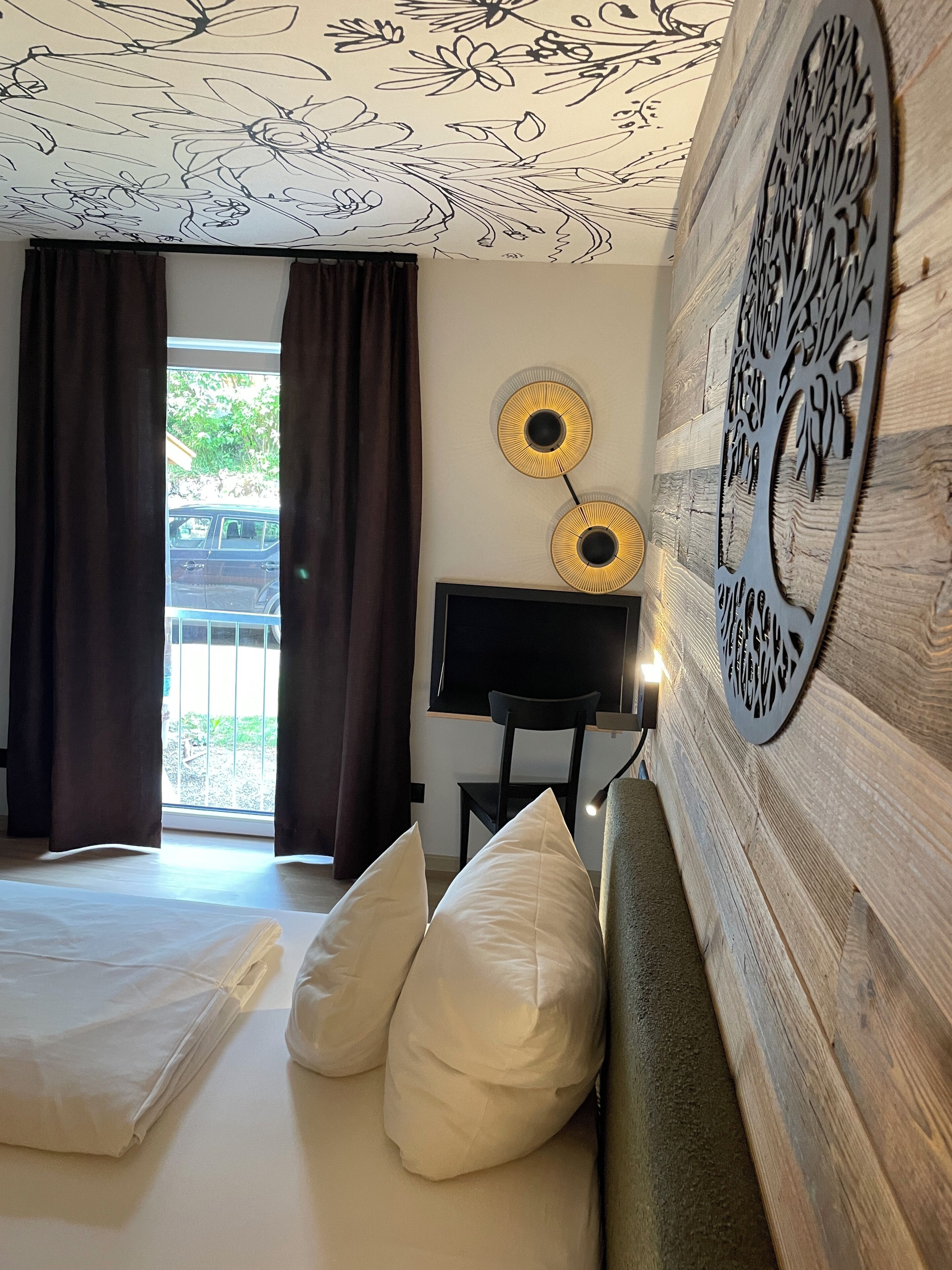 Un dormitorio con cama, una silla, un televisor y un adorno en la pared.