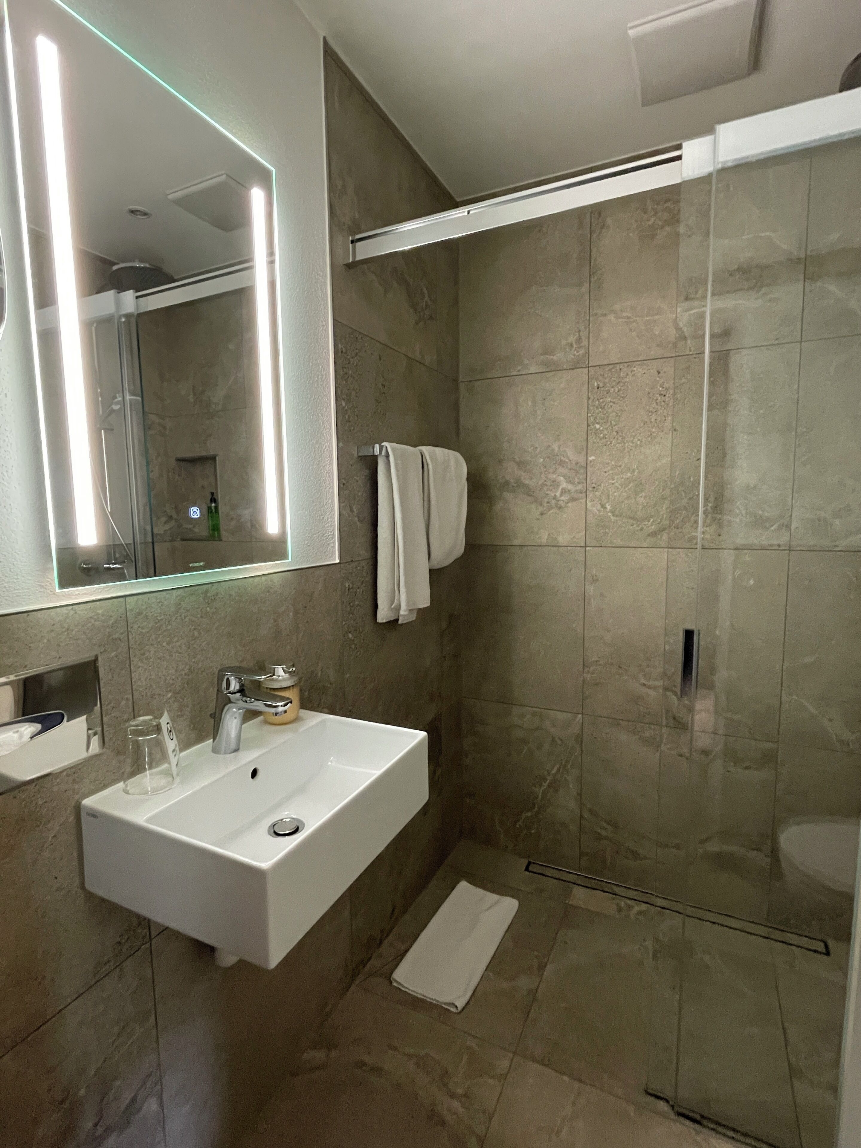 A bathroom with a white sink, mirror, and shower.