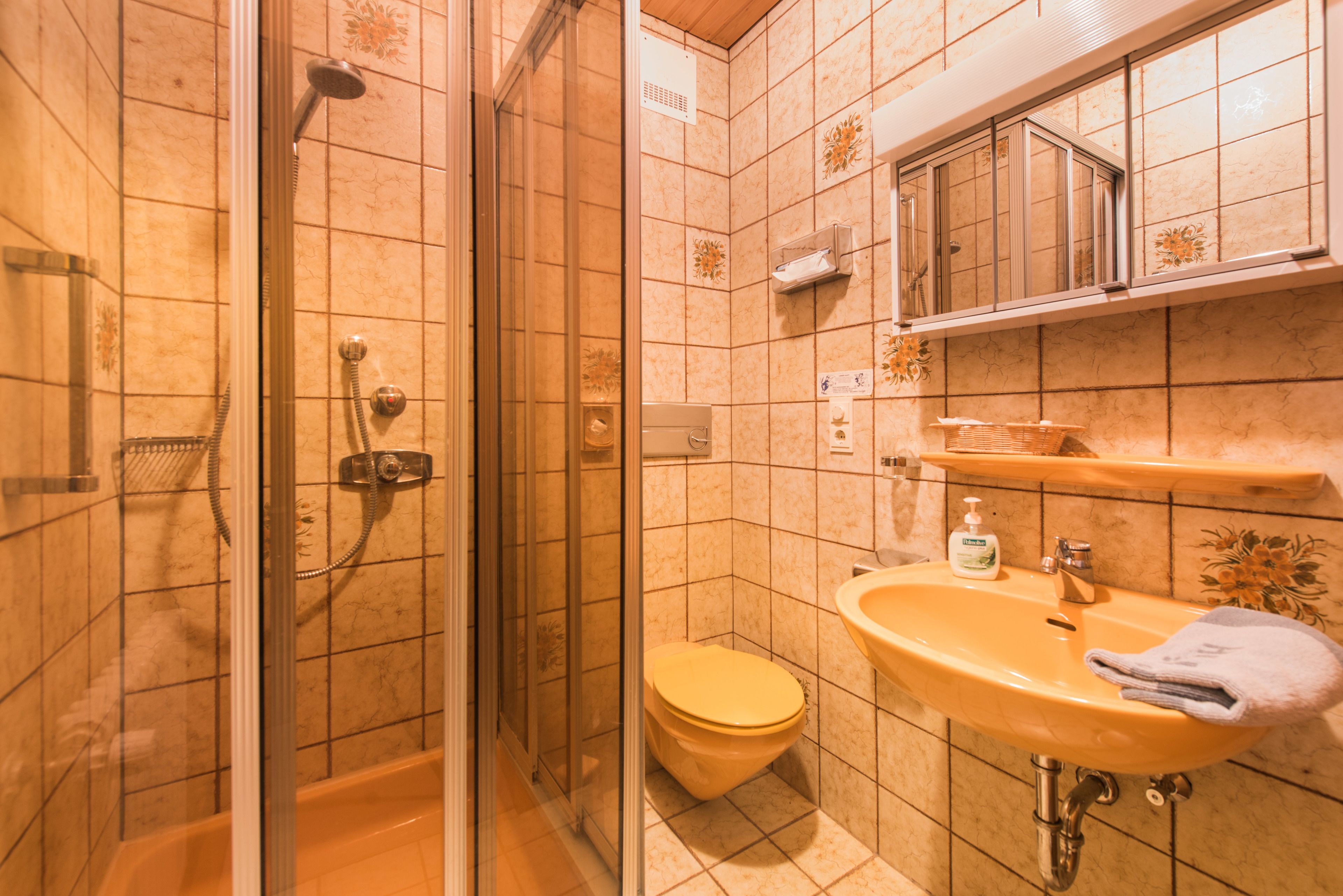 Ein Badezimmer mit einer Duschkabine, einer Toilette und einem Waschbecken mit Handtuch.