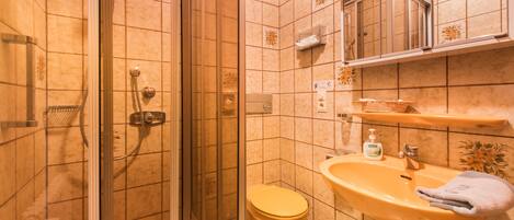 Un baño con ducha de vidrio, inodoro y lavamanos con toalla.