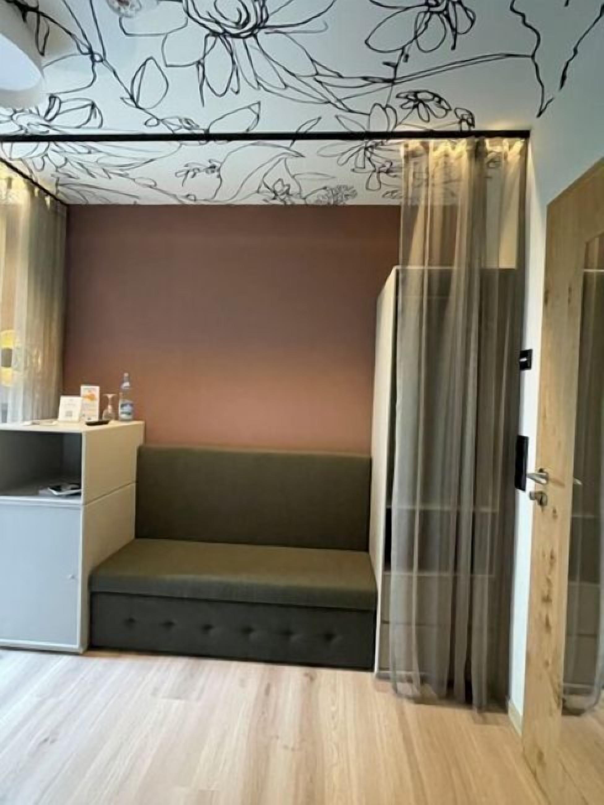 Una habitación con un sofá, una mesita, un armario y una puerta con cortina.