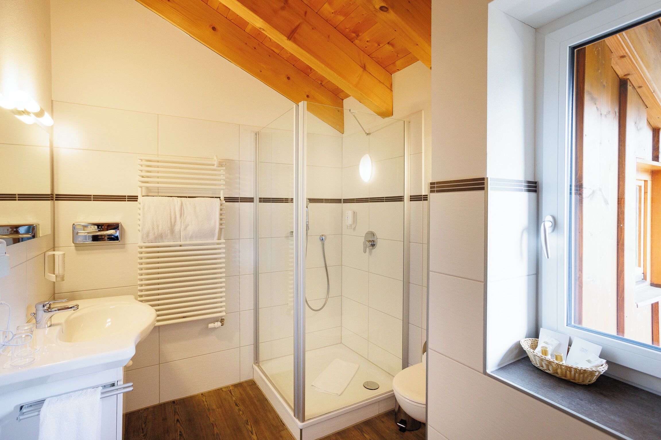 Une salle de bain moderne avec une douche en verre, un lavabo blanc et une fenêtre offrant une belle vue.
