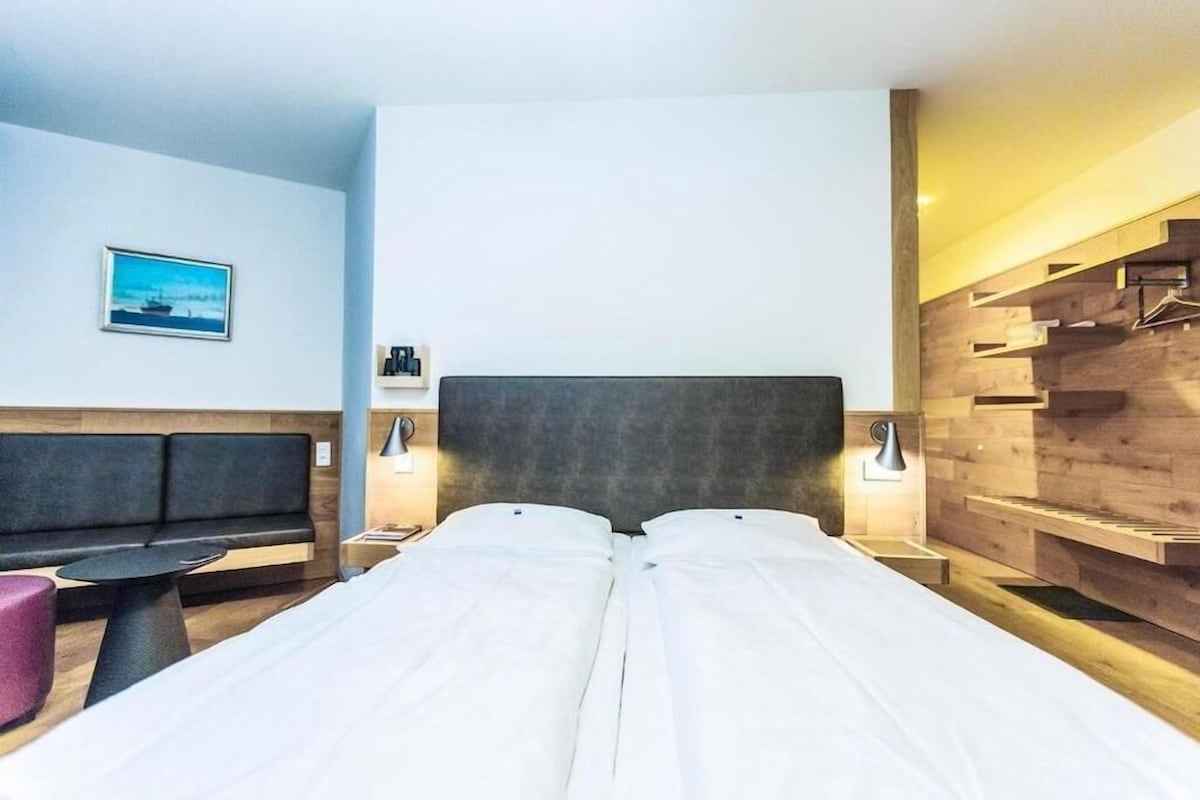 Ein Hotelzimmer mit einem Bett, Nachttischen, einer Couch und einem kleinen Tisch.