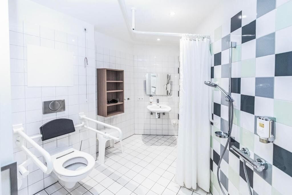A modern bathroom with a white toilet, a shower, a sink, and a mirror.