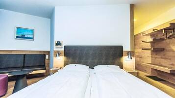 Una camera d'albergo con un letto, un angolo salotto, un tavolino e una mensola a muro.