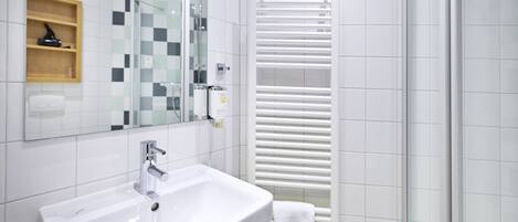 A modern bathroom with a white sink, a mirror, and a towel rack.