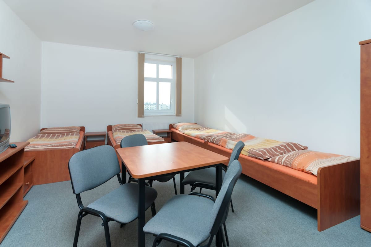 A compact room with a wooden table, two chairs, a sofa, and a television.