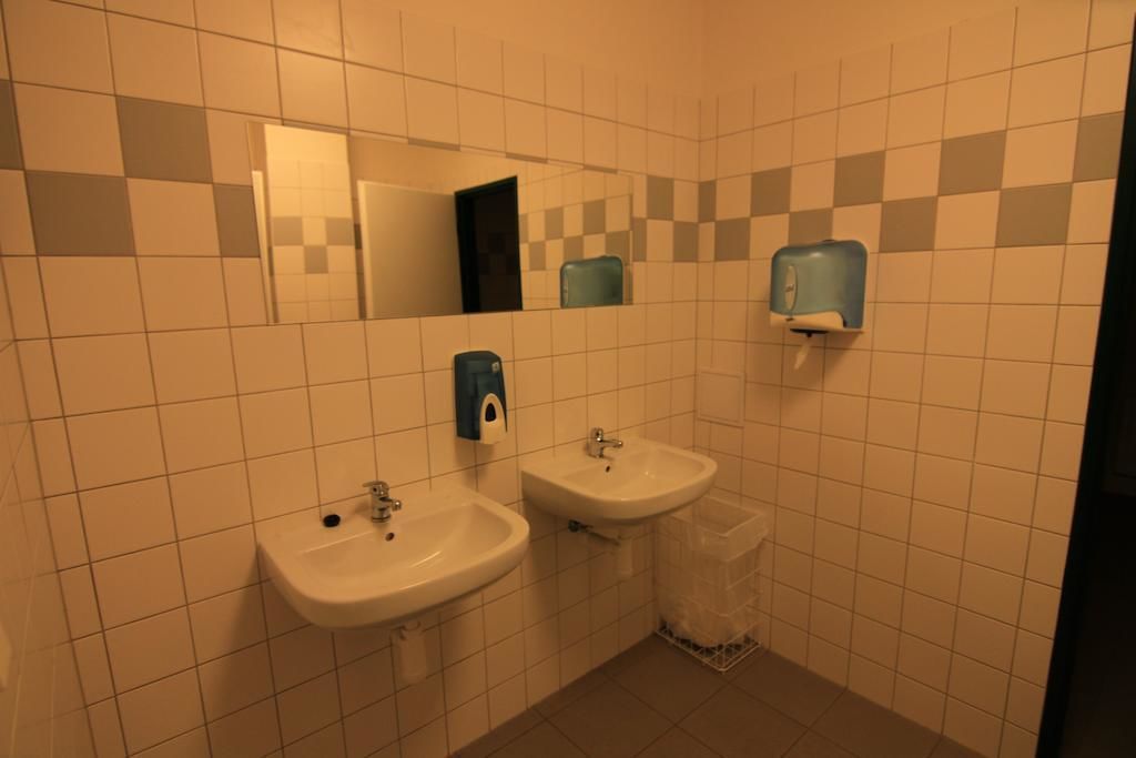 Baño con dos lavamanos, un espejo y un cubo de basura.