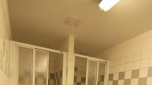 A bathroom with a shower, tiled walls, and a plain floor.