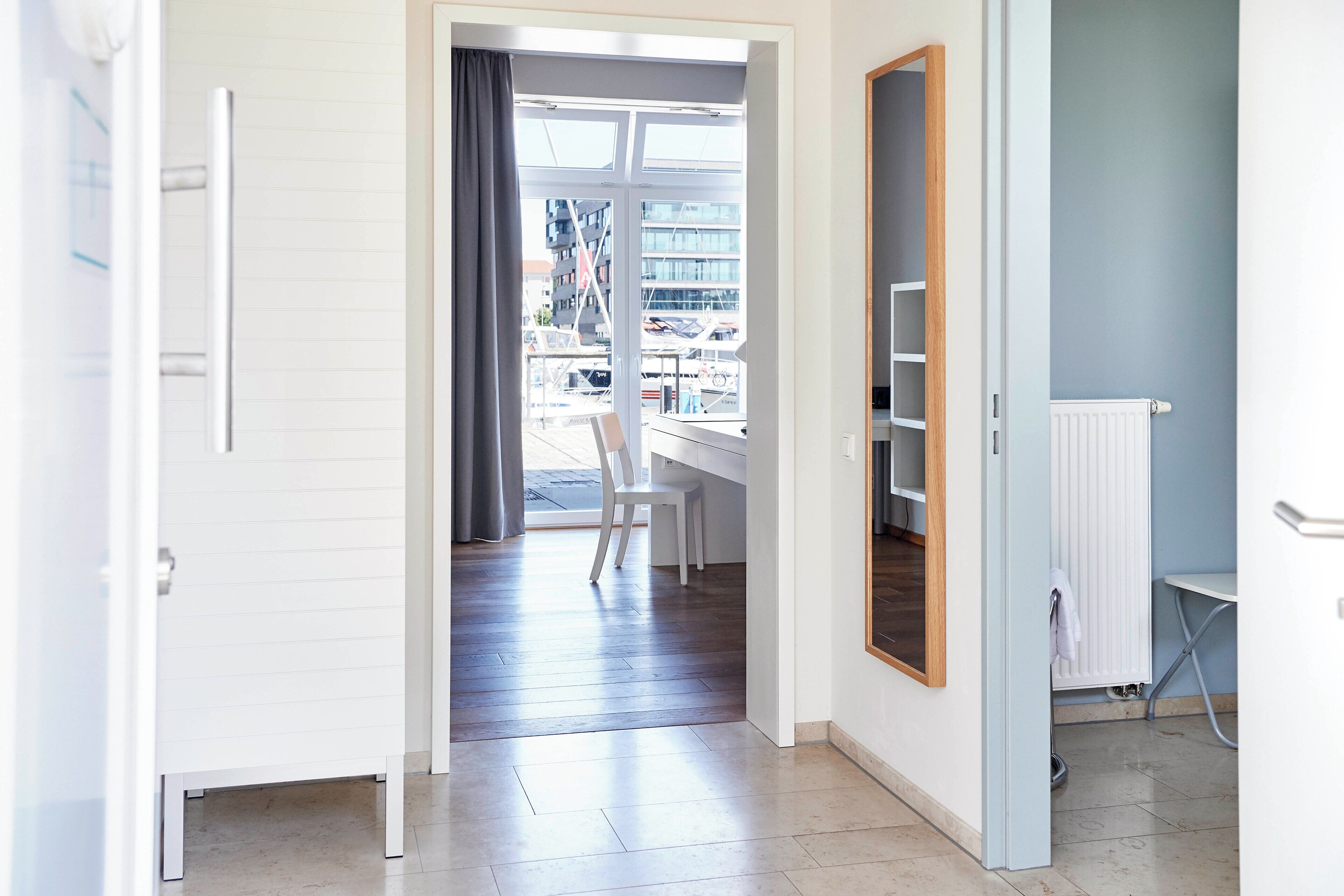 An open doorway leading to a room with a white desk, a chair, and a radiator.