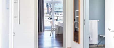 Una puerta abierta que da a una habitación con un escritorio blanco, una silla y un radiador.